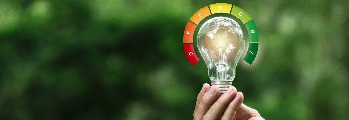 Hand hält Glühbirne mit Energieeffizienzklassen
